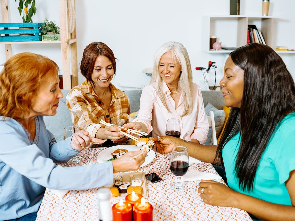Middle-aged women sharing sushi and wine