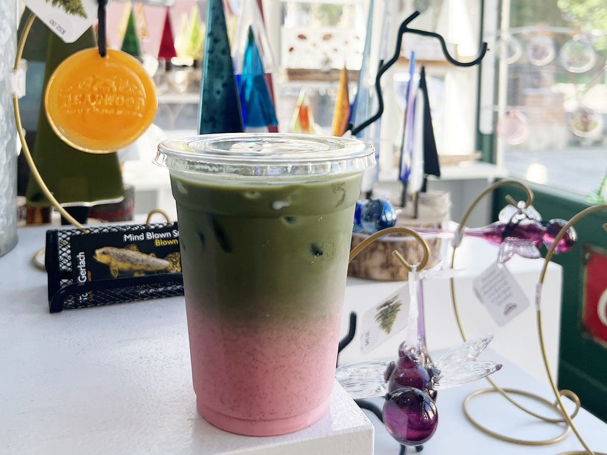 Raspberry cloud matcha iced drink sitting in a display of hand blown glass gifts for sale at Mind Blown Studio