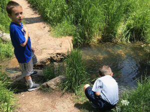 little devils tower trail boy diping hand in creek 300x225