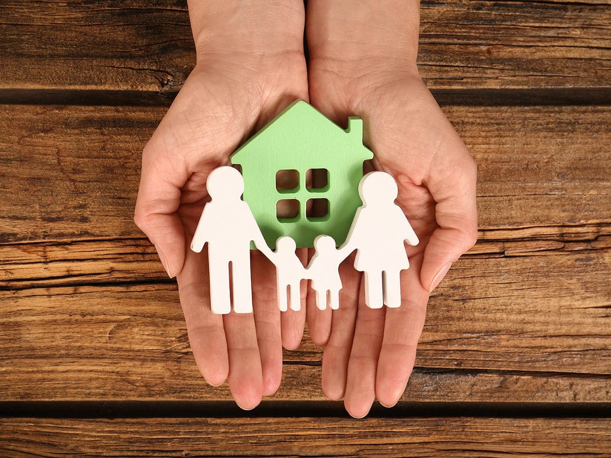 woman's hands holding wooden figures of family and home