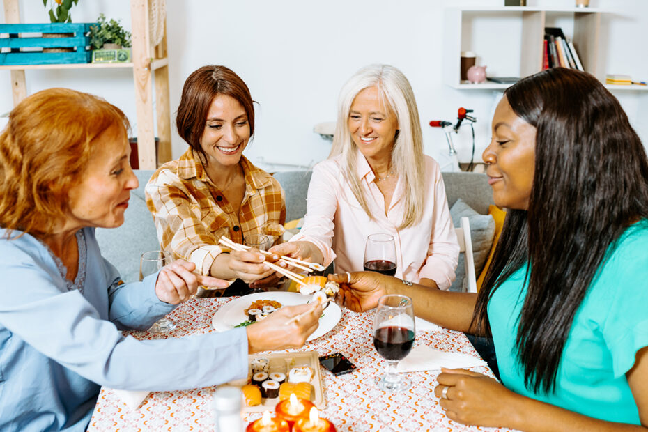 Middle-aged women sharing sushi and wine