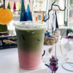 Raspberry cloud matcha iced drink sitting in a display of hand blown glass gifts for sale at Mind Blown Studio